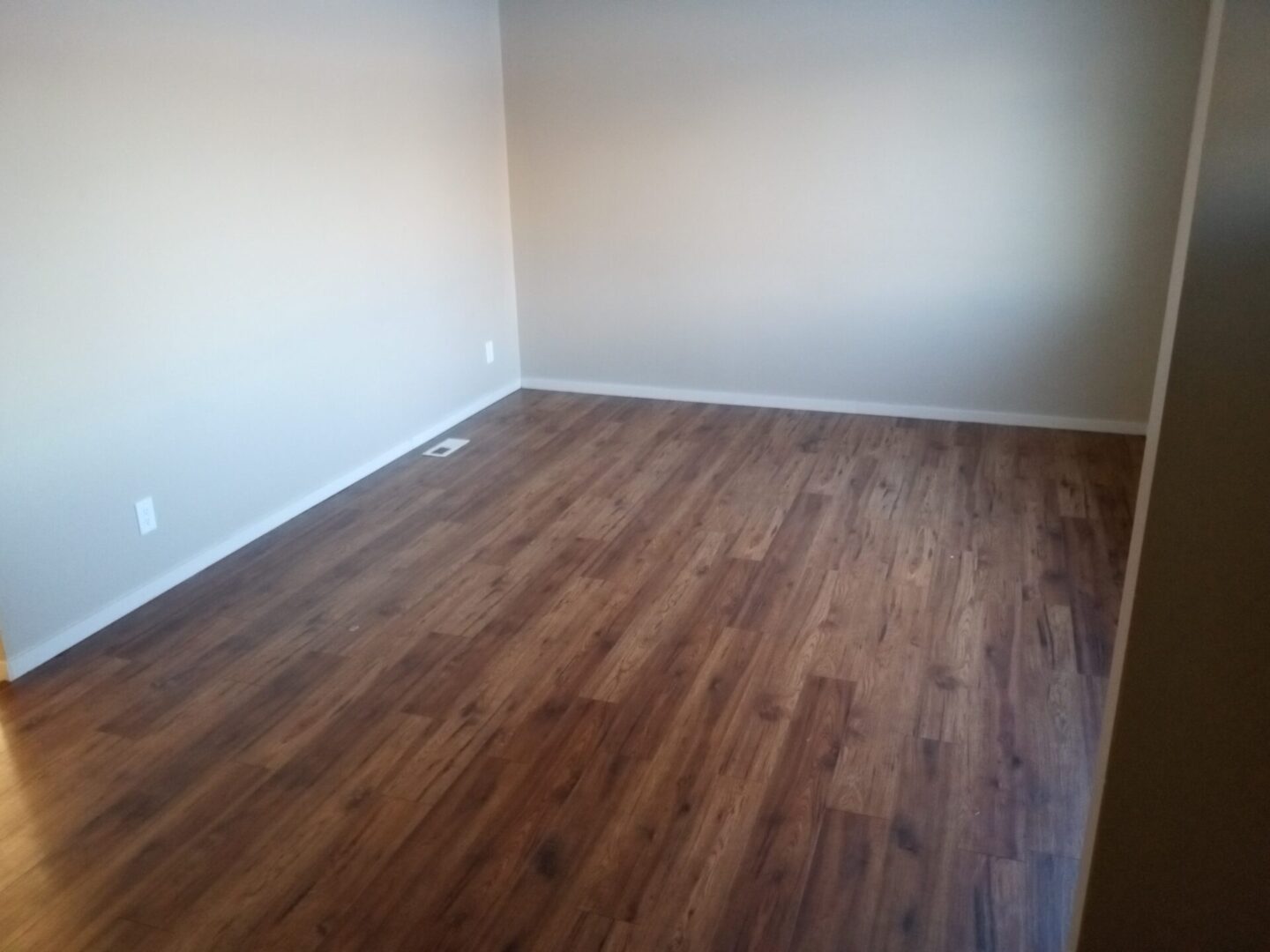 An empty room with wood floors and white walls.