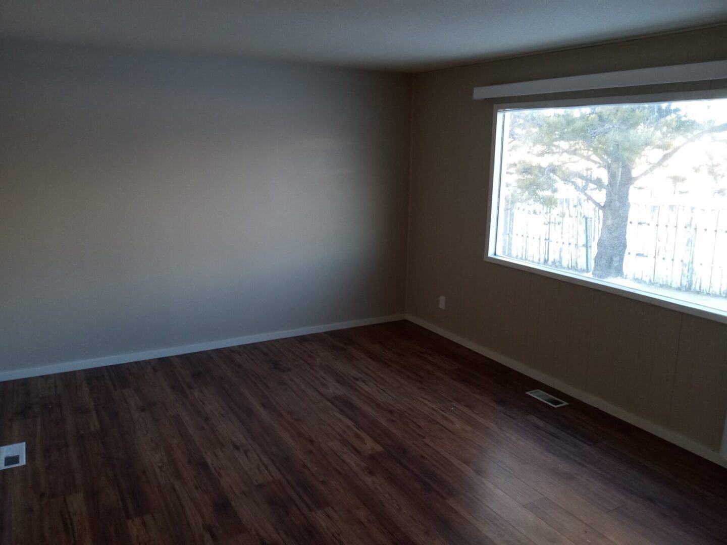 An empty room with hardwood floors and a window.