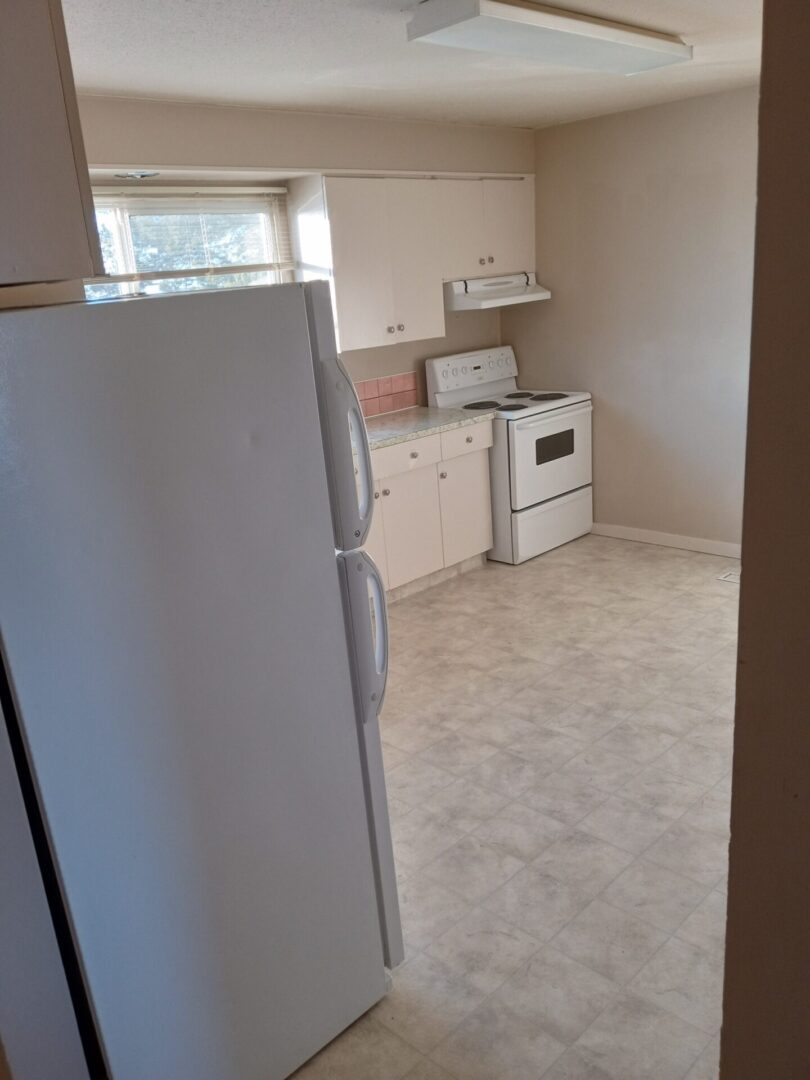 A kitchen with white appliances and a refrigerator.