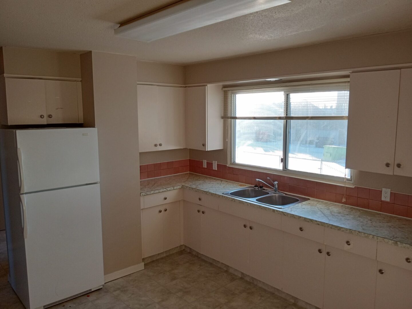 A kitchen with white cabinets and a window.
