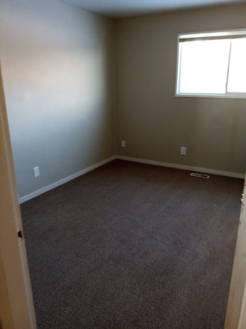 An empty room with carpet and a window.