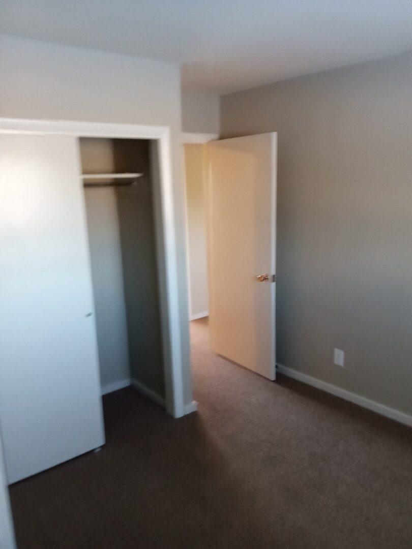 An empty room with a closet and closet doors.
