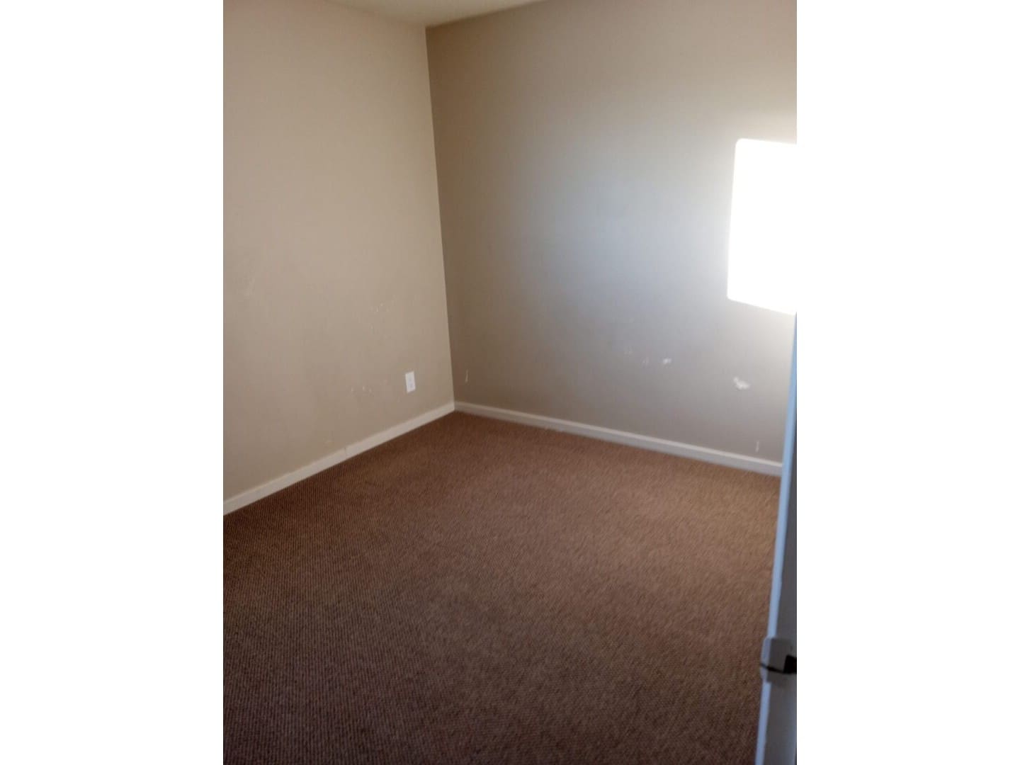 A room with a window and carpet on the floor