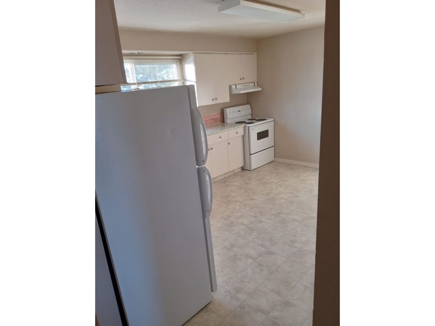 A kitchen with white appliances and beige tile floors.